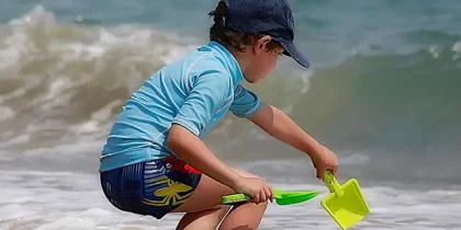 dicas-de-estimulo-sensorial-e-fisico-nas-brincadeiras-na-praia-menino-brincando-na-praia
